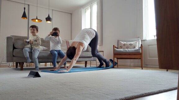 一名妇女在隔离期间在家和她的孩子练习瑜伽