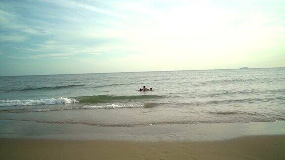 幸福的一家人在海滩上牵着手走向大海