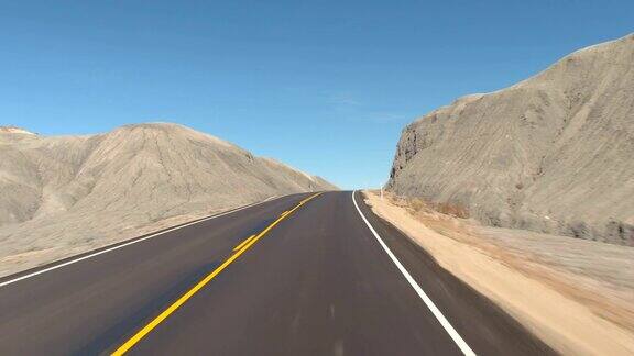 FPV:驾驶沿着空的道路通过灰色的沙漠峡谷在犹他州美国