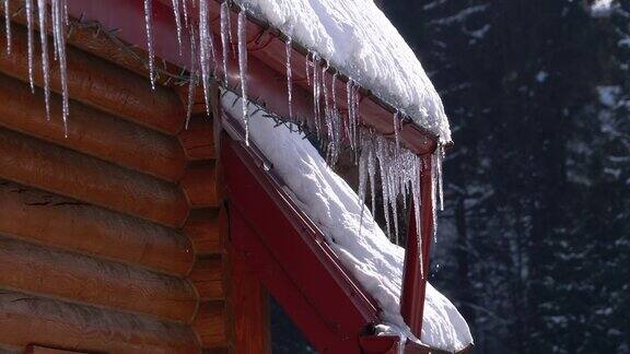 挂在木屋屋顶上的冰柱在阳光下融化滴落慢动作