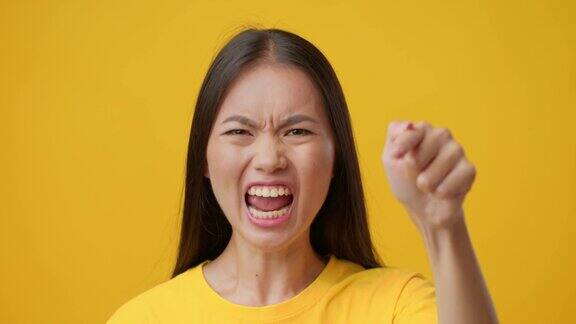 愤怒的韩国女性用手指指责某人黄色背景