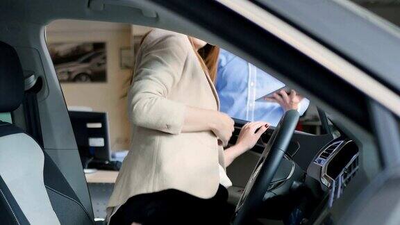 快乐的年轻女子检查汽车内部并向推销员竖起大拇指