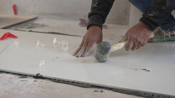 近距离的勤杂工应用粘合剂水泥到地板上并在公寓地板上安装瓷砖