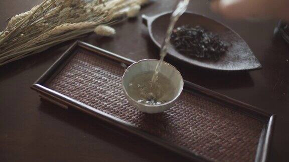 将滚烫的中国茶倒入漂亮的陶瓷茶杯中