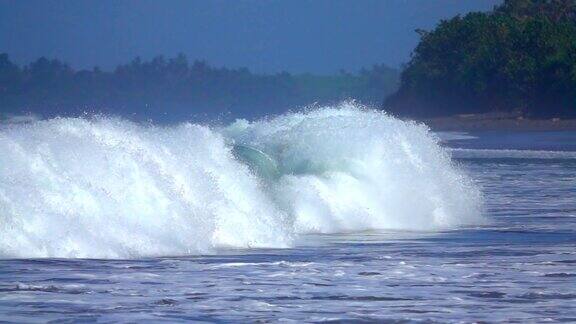 慢镜头:冲岸大浪冲击着沙洲溅起闪闪发光的水珠