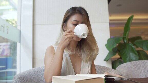 女孩一边看书一边喝咖啡