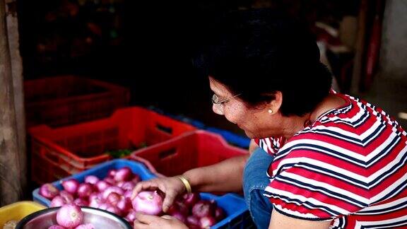 资深亚洲印度妇女从蔬菜水果店购买蔬菜