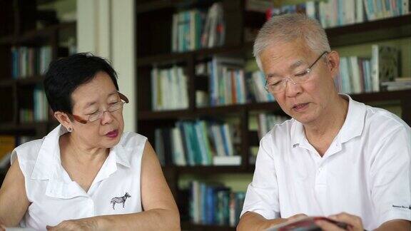 亚洲资深夫妇一起在小图书馆看书和杂志学习与研究概念
