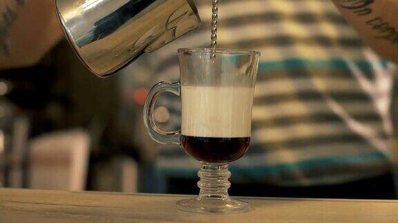 咖啡师将牛奶倒入咖啡玻璃杯中准备拿铁咖啡
