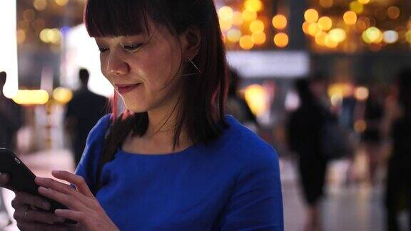 年轻女子在城市中使用美丽的散景手机