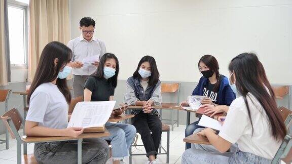 戴着口罩坐在大学教室里的学生