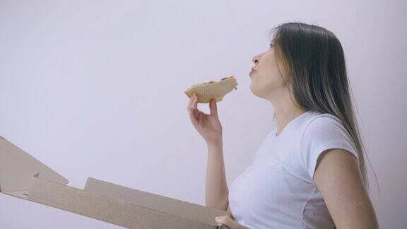 孕妇吃美味的披萨盒在光墙