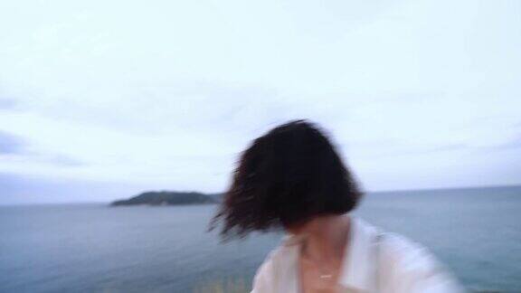 性感的女人站在悬崖边以大海为背景表演爵士舞