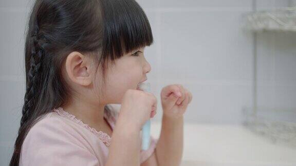 亚洲可爱的小女孩或小孩在浴室用牙刷刷牙口腔卫生保健理念