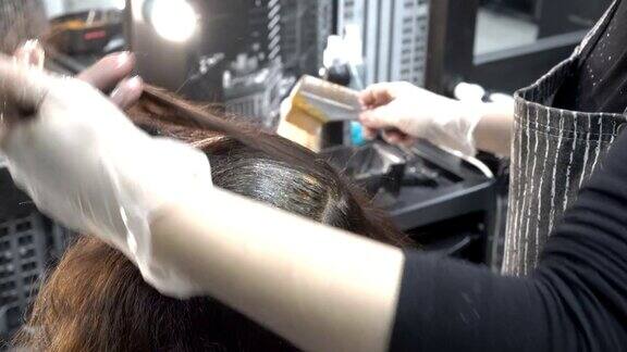 理发师在理发店里涂头发她把女孩的头发分成几缕然后用刷子在上面涂上颜料头发护理关闭了从上后方的视图4k