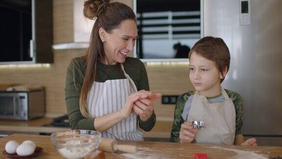 快乐的妈妈和儿子一起在厨房里做饼干家庭日烹饪母子概念慢动作