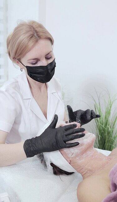 美容师用手从女性脸上取下化妆面膜