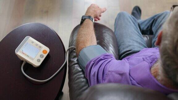 老人在家用自动血压仪检查血压