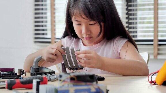 女孩在家里用电脑构建和编程并建造一个机器人手臂作为学校的科学项目她对自己的工作非常满意