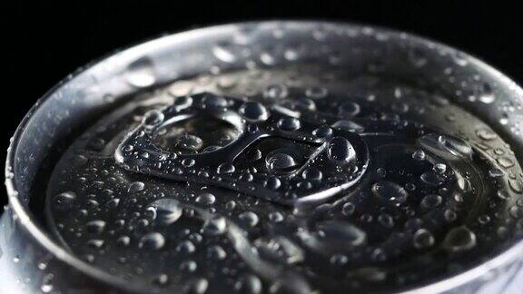 一杯冷饮在黑色背景下旋转苏打水或啤酒铝罐上的水滴