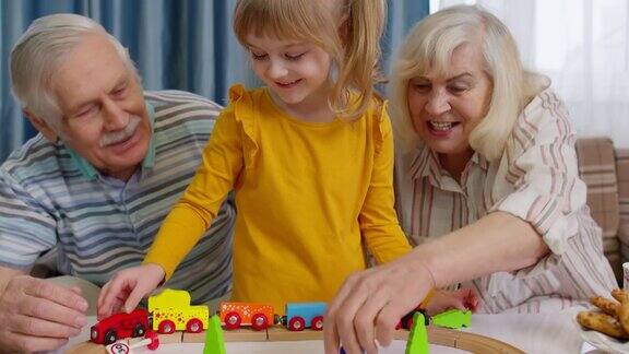 老爷爷奶奶带着小孙子在家里玩游戏在火车上玩玩具火车