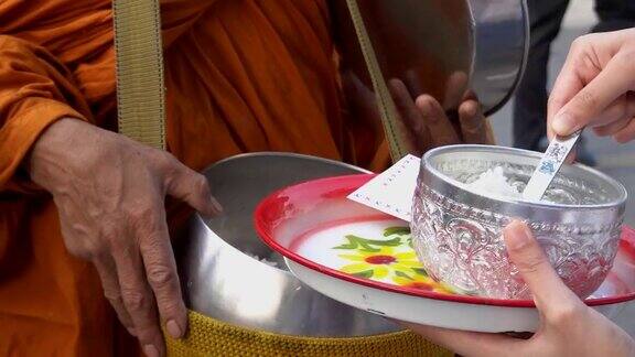 在泰国一名妇女正在给佛教僧侣提供食物