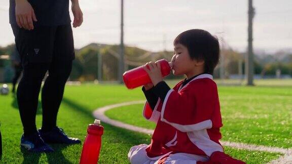 女足或足球队教练帮助小孩喝水