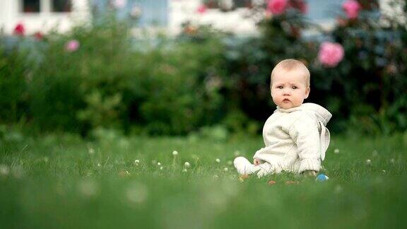 可爱的蹒跚学步的婴儿白天在公园的草地上玩耍