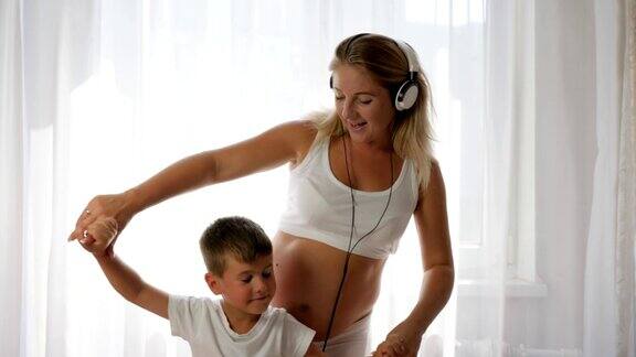年轻的妈妈抱着儿子的手听音乐戴着耳机跳舞