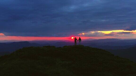 这对夫妇拿着烟火棒站在一座以日出为背景的山上
