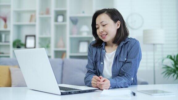 亚洲女性坐在办公室里用笔记本电脑进行视频通话