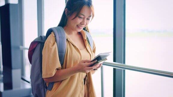 幸福的亚洲女性乘客持机票和护照走在机场候机楼出国旅游