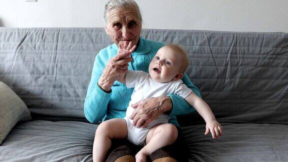 一位带着海象的老祖母坐在沙发上怀里抱着一个小孙子
