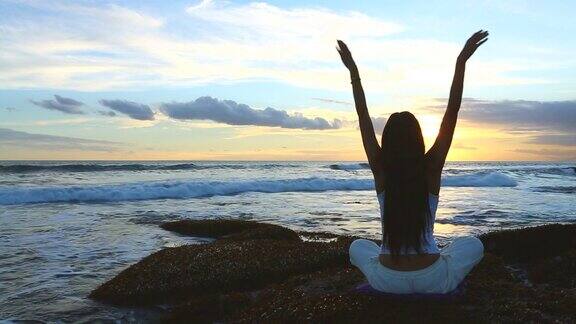 日落时分年轻女子在海边练习瑜伽