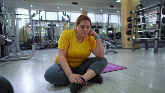 年轻超重女性在健身房锻炼后休息