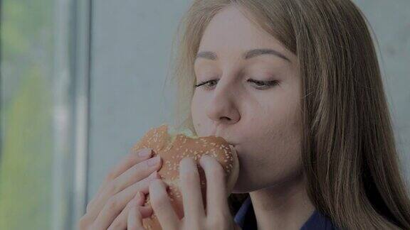 漂亮的女孩吃了一个汉堡快餐店