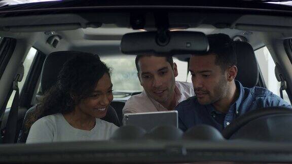 幸福的不同的夫妇购买汽车在经销商和交谈同时看平板电脑上的细节