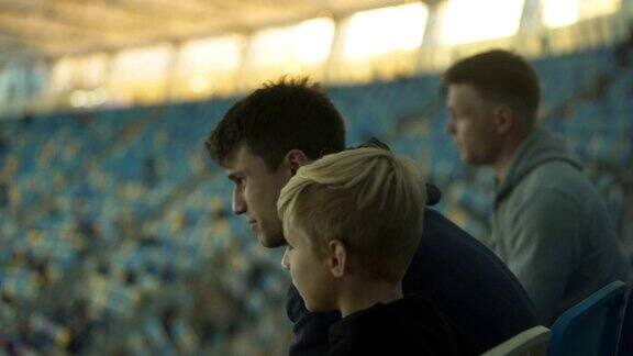 兄弟俩在体育场看少年足球比赛讨论输掉的比赛