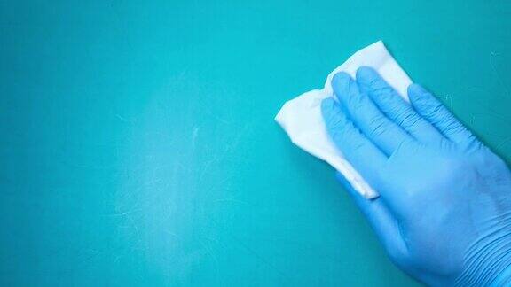 手戴蓝色橡胶手套用布清洁桌子