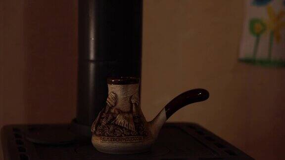 用手把陶瓷壶放在旧炉子上煮咖啡