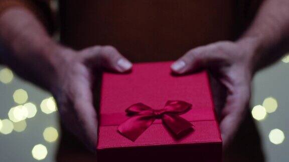 年轻人赠送了一份关于散景背景的礼物红色礼品盒与红色丝带开