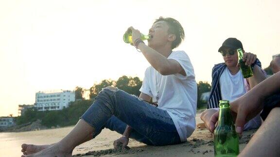 年轻的亚洲成年人悠闲地坐在海滩上喝啤酒