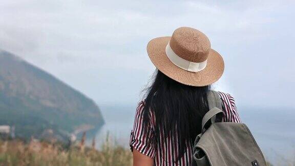 后视镜优雅女子旅行家背着背包走在山顶欣赏自然景观