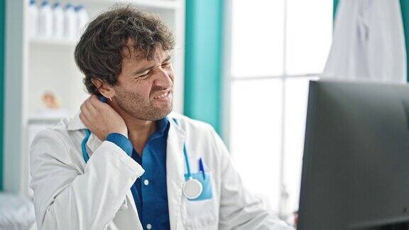 年轻的西班牙裔医生在诊所使用笔记本电脑强调颈椎疼痛
