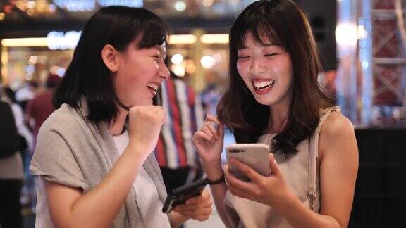两个年轻的女性朋友在城市里使用智能手机