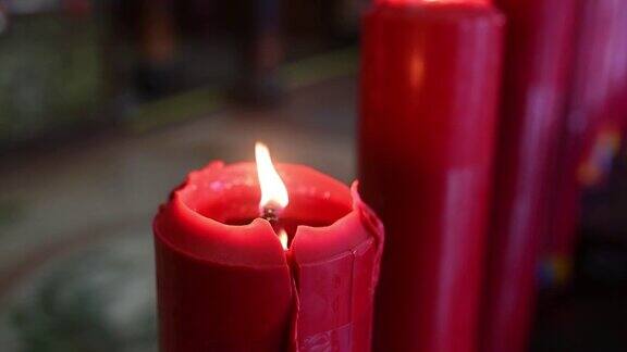 接近融化的红色蜡烛和火焰火焰与黑暗的背景