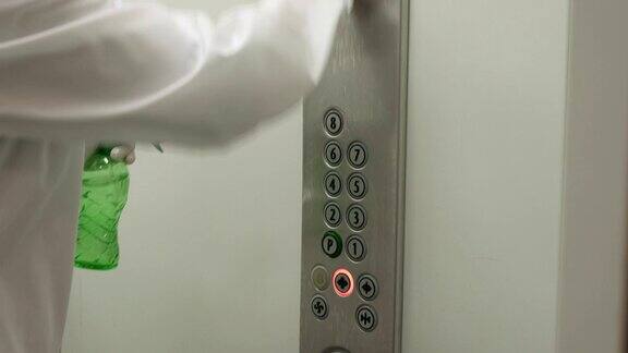 一名妇女用湿纸巾和酒精消毒剂喷雾清洁电梯按钮控制面板消毒卫生保健抗冠状病毒病
