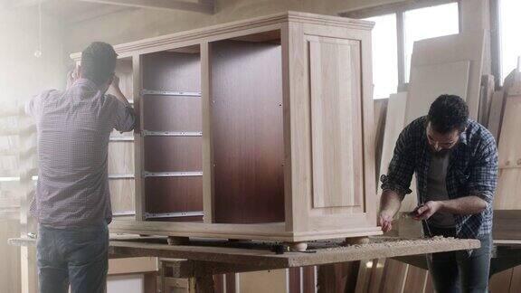 两个木匠在木匠店里一起做一件大家具