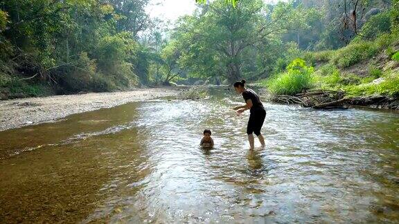 小男孩和妈妈一起在小溪里玩耍