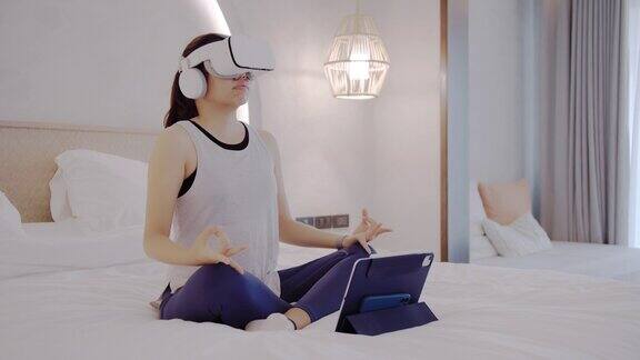 亚洲女性在家里的卧室里使用VR眼镜锻炼身体